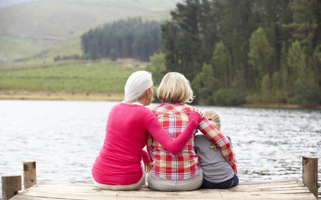 Mother, daughter and grandmother sitting on a jetty